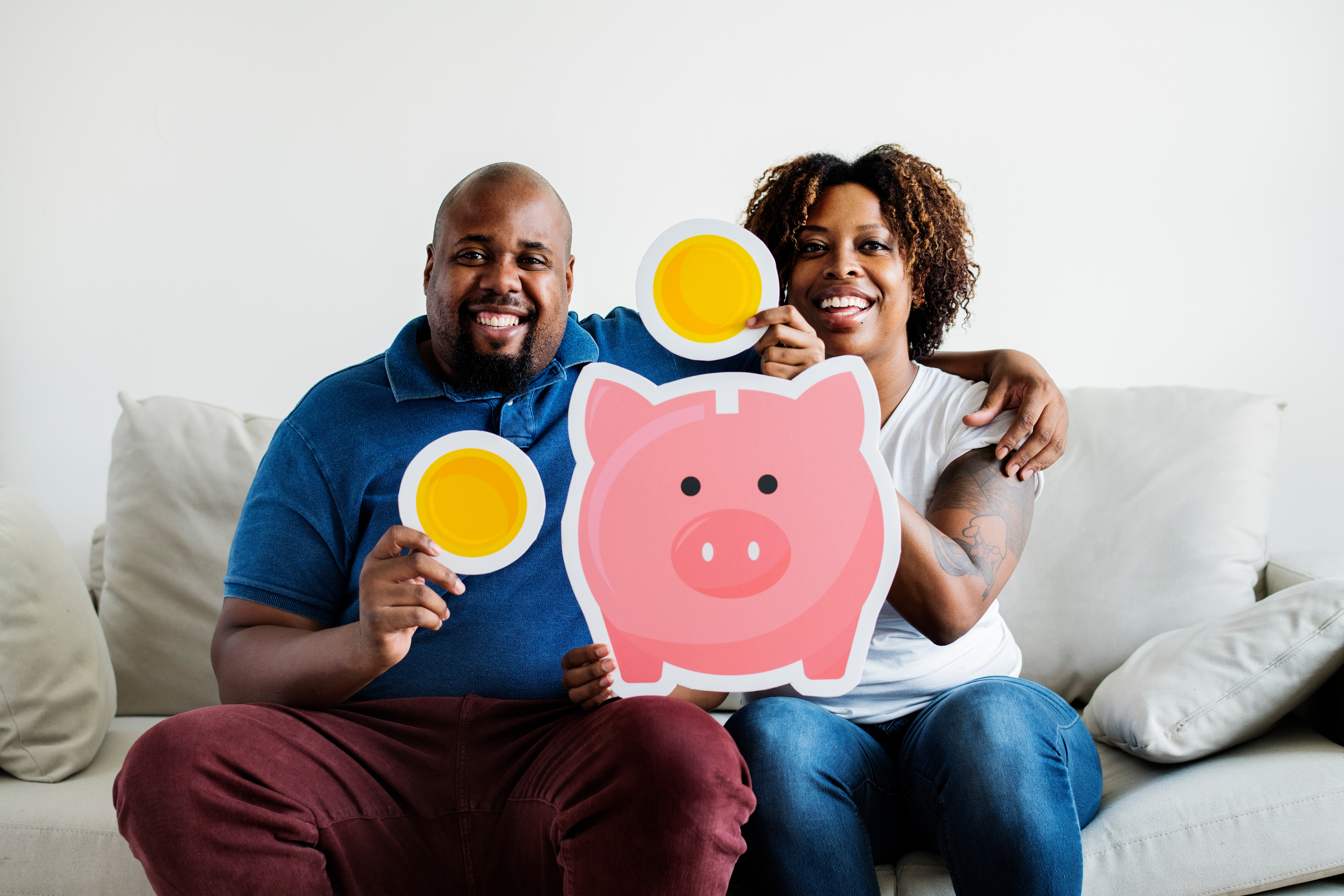 Smiling couple with cutout of piggy bank and coins.