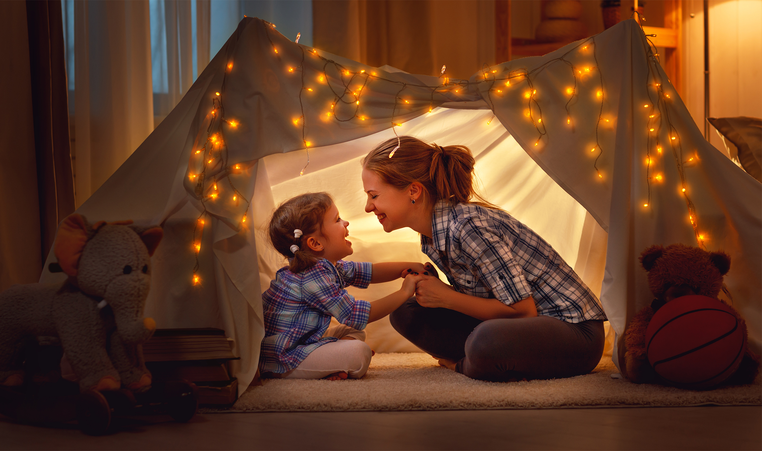 Mother and daughter in a fort made of blankets