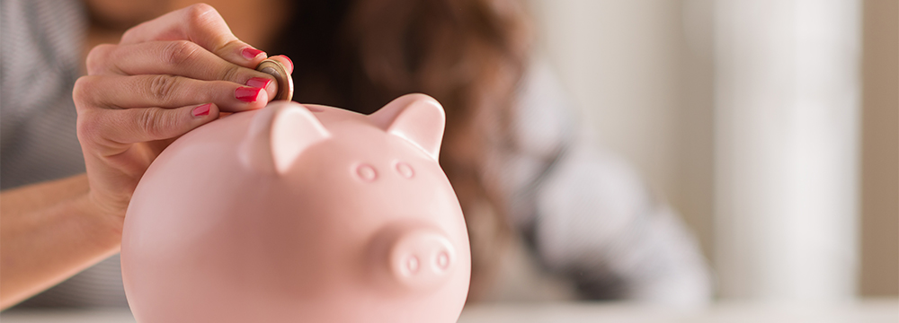 Person putting a coin in a piggy bank